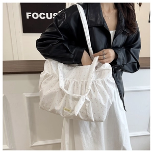 Detailed view of white polka dot tote bag featuring ruffled edges and bow strap accent