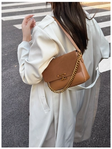 Close-up of brown leather shoulder bag with gold chain and large T-shaped buckle