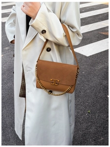 Detail of a brown leather shoulder bag with gold metal logo and suede texture panels