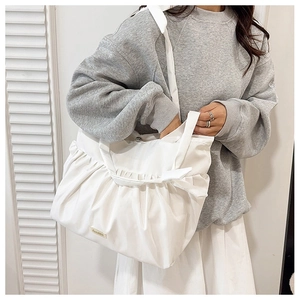 Detail showing the white pleated tote bag texture and brand label on model