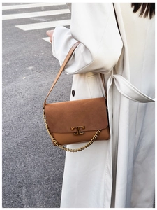 Detail showing the brown suede and leather textures with a gold logo and metal chain strap