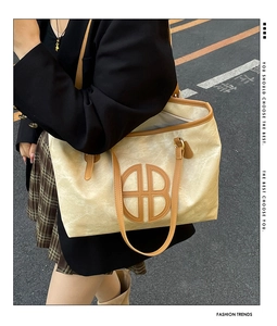 Close-up of vintage beige tote bag featuring brown trim and circular logo detail