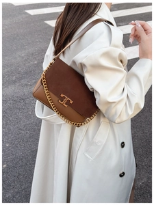 Close-up of golden double-T logo on brown suede and leather patchwork handbag