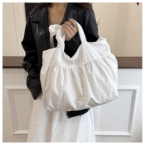 Close-up of white tote bag with pink polka dots, ruffle design and cute bow handle