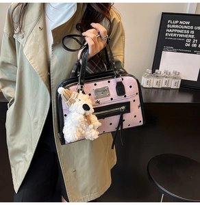 Pink polka dot tote bag detail with luxury black trim and cute plush puppy charm accessory