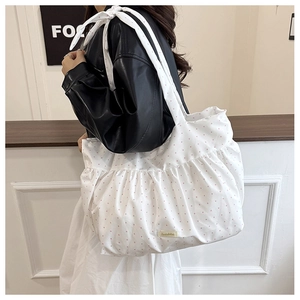 Detail view of a white polka dot tote bag with a large decorative shoulder bow