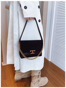 Close-up of black crossbody bag with gold logo and suede leather patchwork texture