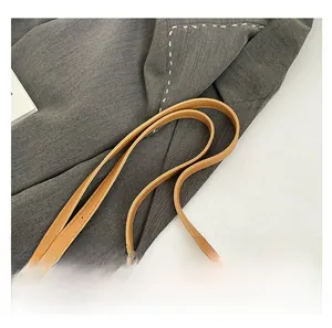 Detail of brown leather adjustable strap with gold buckles on a canvas tote bag