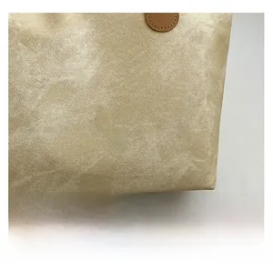 Close-up of champagne pearl luster fabric with twill texture and brown leather handle