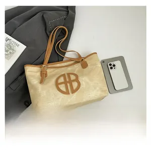 Comparaison de taille du cabas en toile beige avec finitions cuir marron et logo près du mobile