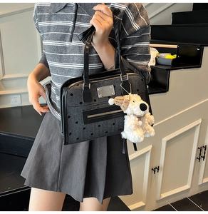 Detail of dark grey polka dot handbag with black straps and a cute plush dog pendant