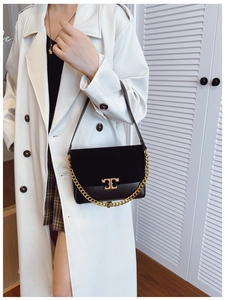 Macro detail of black leather crossbody bag with suede panel and gold T-logo hardware