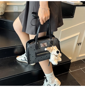 Detailed view of polka dot fabric bag featuring a cute plush puppy charm and metallic logo