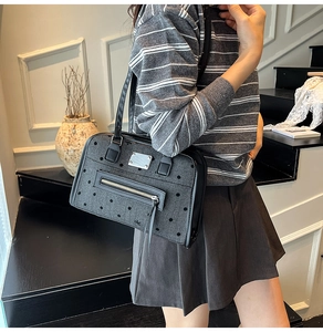 Detail of grey polka dot tote bag showing the zipper pocket and black leather straps