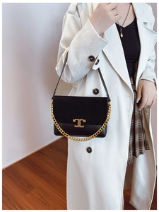 Detail of black leather and suede bag with gold metal T-clasp and chain strap