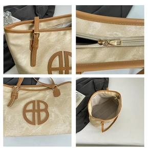 Detail view of the beige canvas tote bag with brown leather trim and metal buckles