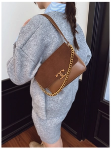 Detail of vintage brown patchwork leather bag with gold chain and metal buckle on model
