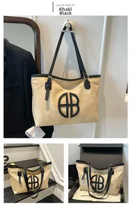 Detail of khaki canvas tote bag with black leather trim and circular logo decoration