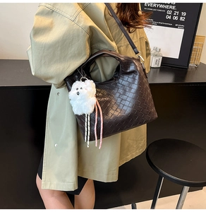 Detailed close-up of dark brown woven bucket bag with cute plush bear charm for autumn