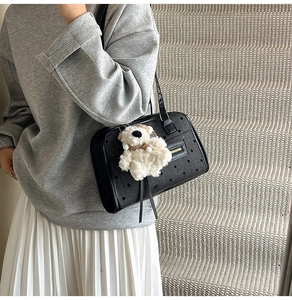 Close-up of black polka dot shoulder bag with a cute white plush bear pendant detail