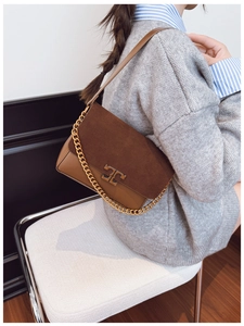 Detail of dark brown suede crossbody bag with gold chain and metal double T buckle