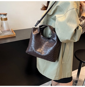 Detailed side view of dark brown woven leather bucket bag worn by model in a cozy indoor setting