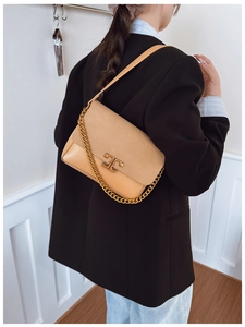 Detail of beige crossbody bag with suede flap, gold chain, and metal T-shaped buckle