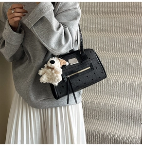 Detail view of polka dot tote bag with silver plaque, tassel zipper, and puppy charm