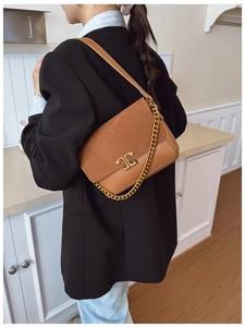 Detail of tan suede shoulder bag featuring a gold chain and T-shaped metallic buckle