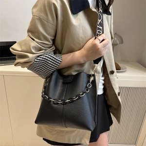 Fashionable black pebble leather bucket bag with gold chain and patterned wide strap