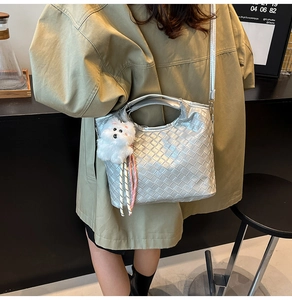 Detail view of silver metallic woven tote bag with a plush puppy charm and long strap