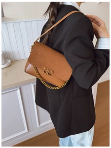 Detail of a brown leather shoulder bag featuring a gold metal logo and crossbody strap