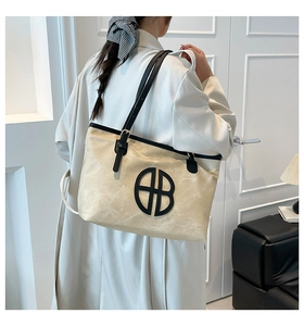 Détail du cabas en toile avec bordure noire et logo sur le tissu de couleur crème