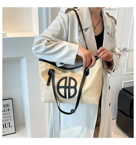Fashionable beige tote bag with black trim and long shoulder straps worn by a model