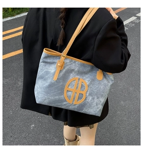 Détail d'un grand sac cabas en toile grise avec lanières en cuir porté par un modèle
