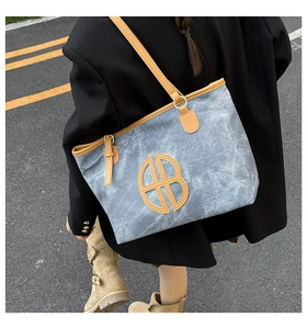 Détail du sac cabas en denim avec finitions cuir et logo AB porté à l'extérieur