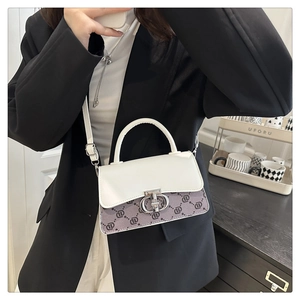 Detail of a color-block flap bag with metal ring buckle worn by a model on shoulder