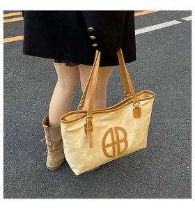 Vue détaillée d'un grand sac cabas avec anses en cuir et logo circulaire à l'extérieur