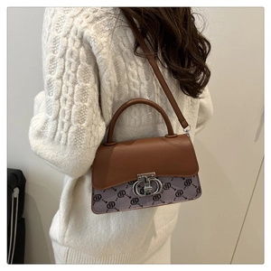 Crossbody view of a vintage brown canvas bag with metal logo clasp and leather strap