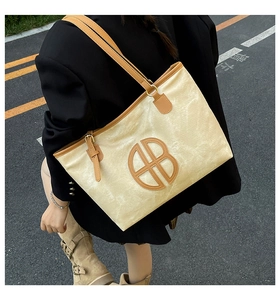 Detail of canvas tote bag with brown leather trim and circular AB logo embroidery