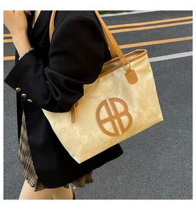 Détail du cabas en toile avec grande découpe logo circulaire et bordure en cuir brun