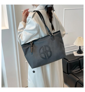 Detailed view of dark grey matte leather tote bag featuring a large embossed logo