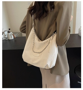 Detailed back view of a white PU tote bag featuring chic silver chain accents on a model