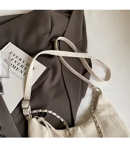Detail of adjustable long shoulder strap and chain on cream half-moon hobo bag