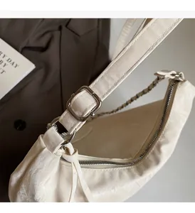 Close-up of cream crescent shoulder bag featuring premium silver metallic hardware