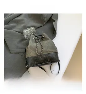 Detailed top view of grey-green bucket bag with chain closure next to a grey blazer