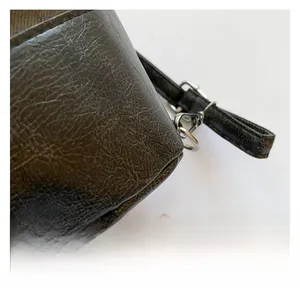 Macro detail of dark brown pebble grain leather bucket bag with metal link connection