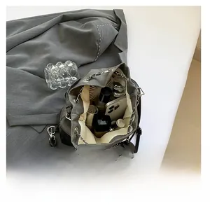 Detail view of large capacity dark grey drawstring bucket bag with makeup and smartphone