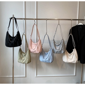 Detail of half-moon tote bags featuring metallic chains and a stylish wrinkled texture