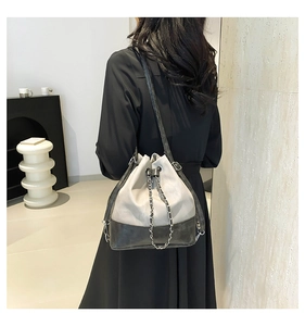Close-up of minimalist bucket bag featuring grey and black leather with silver chain